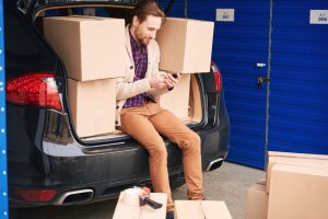 Self storage locker with man moving boxes from vehicle inside.