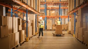 Pallets inside racking with warehouse workers next to them. 