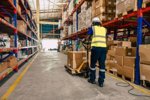 Warehouse worker moving pallet storage through a 3PL in Margate, Kent using a pump truck.