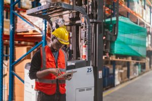 Warehouse worker leaning on forklift next to pallets in the Isle of Wight.