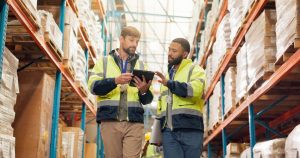 Warehouse workers looking at fulfilment centre's WMS system to support order fulfilment. 