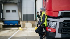 HGV driver standing outside warehouses roller doors for fulfilment and distribution.