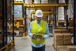 Warehouse worker moving through aisle in 3PL with pallet storage on either side.