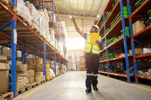 Aisle of pallet storage with a warehouse walking through looking for carton to use in order fulfilment.
