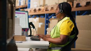 Desk in warehouse with customer information on the computer screen for order fulfilment.