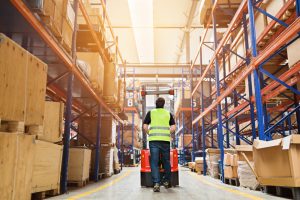Warehouse aisle with pallet storage either side and a forklift moving through.