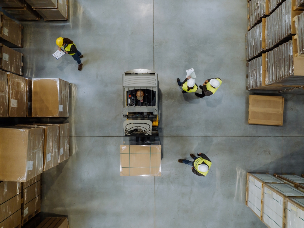 Top down view forklift with pallet storage either side and warehouse workers doing third party logistics. 