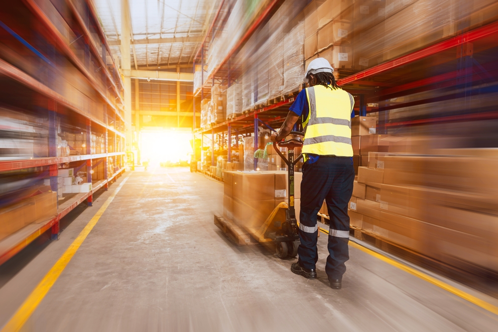 3PL worker walking fast past pallet storage in Christchurch. 