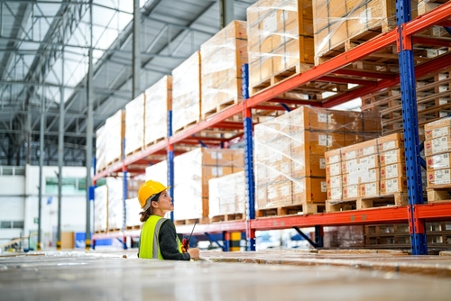 Pallet storage aisle in England warehouse with worker managing stock. 
