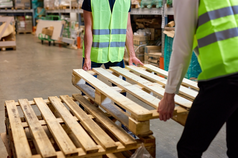 Warehouse workers in Horsham carrying empty pallets ready for storage. 