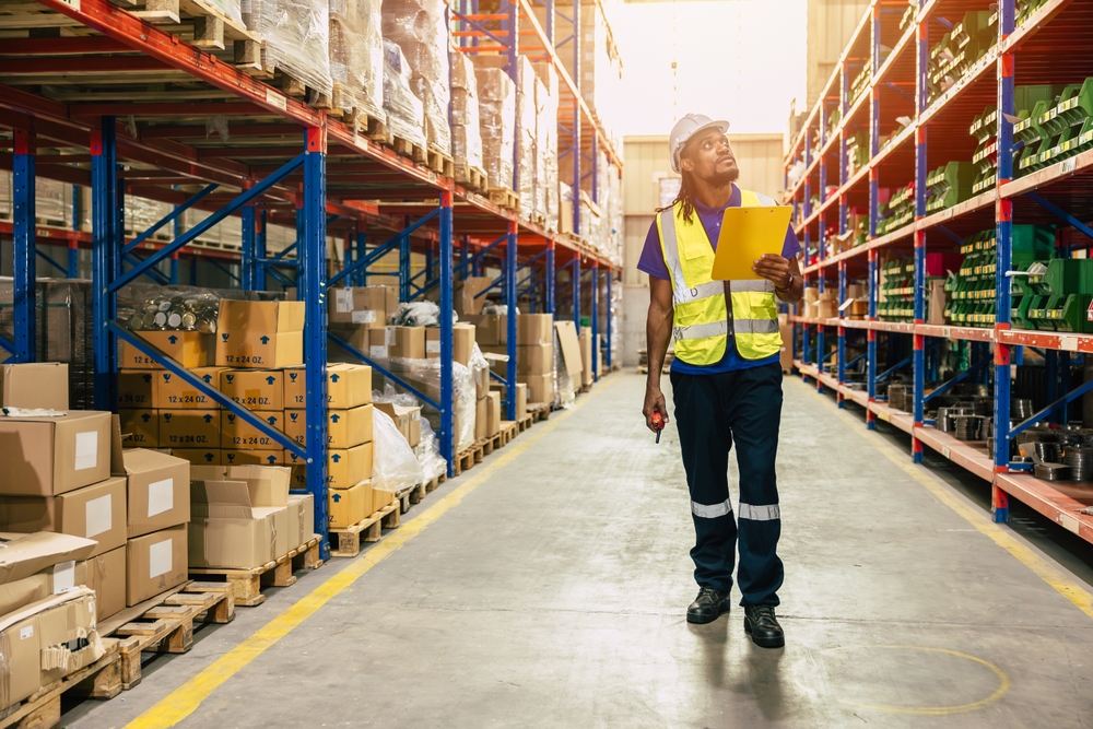 Warehouse worker walking through aisle of pallet storage in Ashton-under-Lyme.