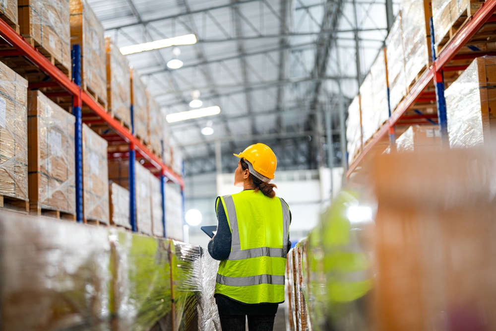 Warehouse worker walking through racked pallet storage aisle in Thundersley.