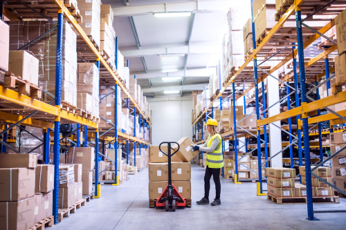 Pallet storage aisle in Havant 3PL with a pallet on a pump truck being moved by a warehouse worker.