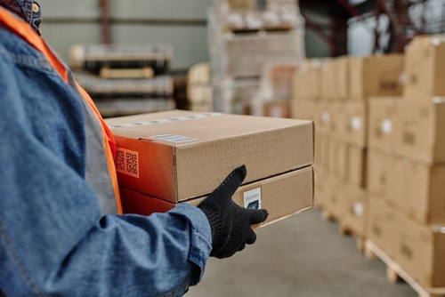 Warehouse worker carrying orders for fulfilment to be labelled and shipped.